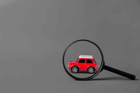 Carro vermelho analisado com lupa: vistoria cautelar